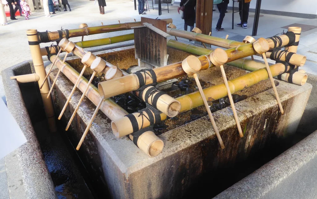 Louches en bois posées sur la fontaine temizuya du sanctuaire Ōsaka Tenman-gū, pour le rituel de purification au Japon
