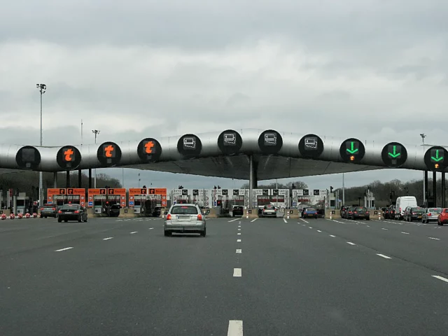 Voitures à l’approche d’une gare de péage sur une autoroute française, à anticiper avec les vignettes pour voyager en 2026