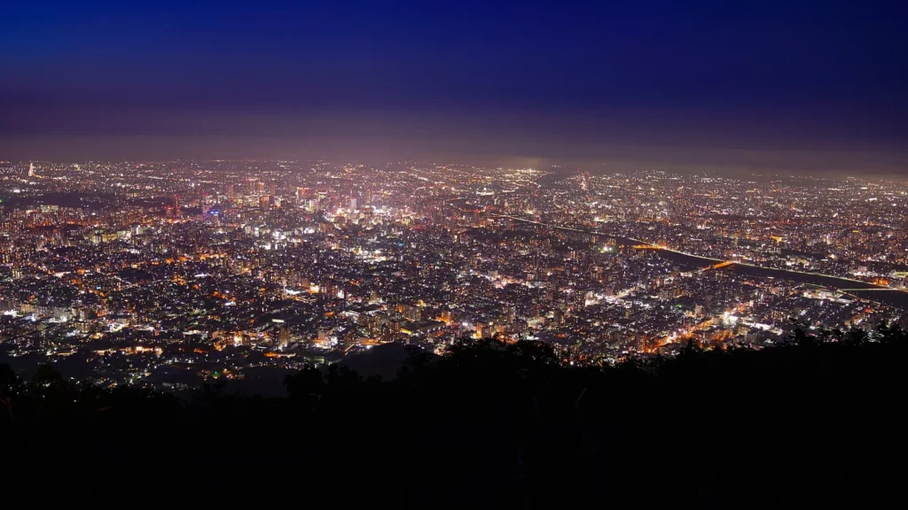 Panorama nocturne de Sapporo depuis le sommet du mont Moiwa, la ville illuminée au pied des montagnes de Hokkaido