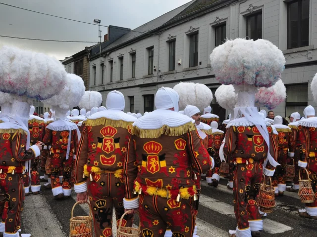 Gilles de Binche vus de dos en costume brodé de lions et chapeau de plumes d’autruche, emblème du folklore belge au carnaval