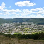Méandre de la Meuse enserrant la ville de Revin entre les collines boisées des Ardennes françaises, sous un ciel d'été
