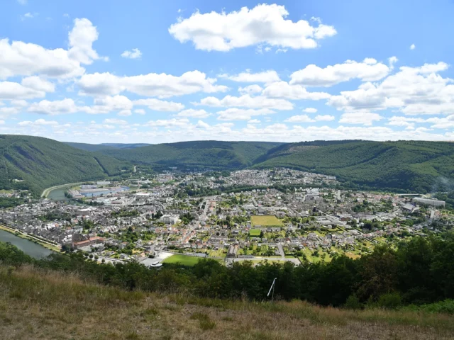 Méandre de la Meuse enserrant la ville de Revin entre les collines boisées des Ardennes françaises, sous un ciel d'été