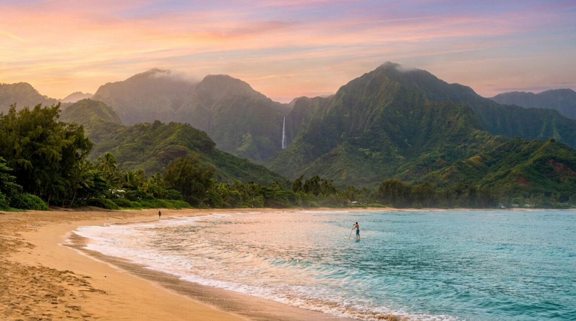 Personne faisant du paddle sur une plage d'Hawaï avec des montagnes verdoyantes et une cascade en arrière-plan.