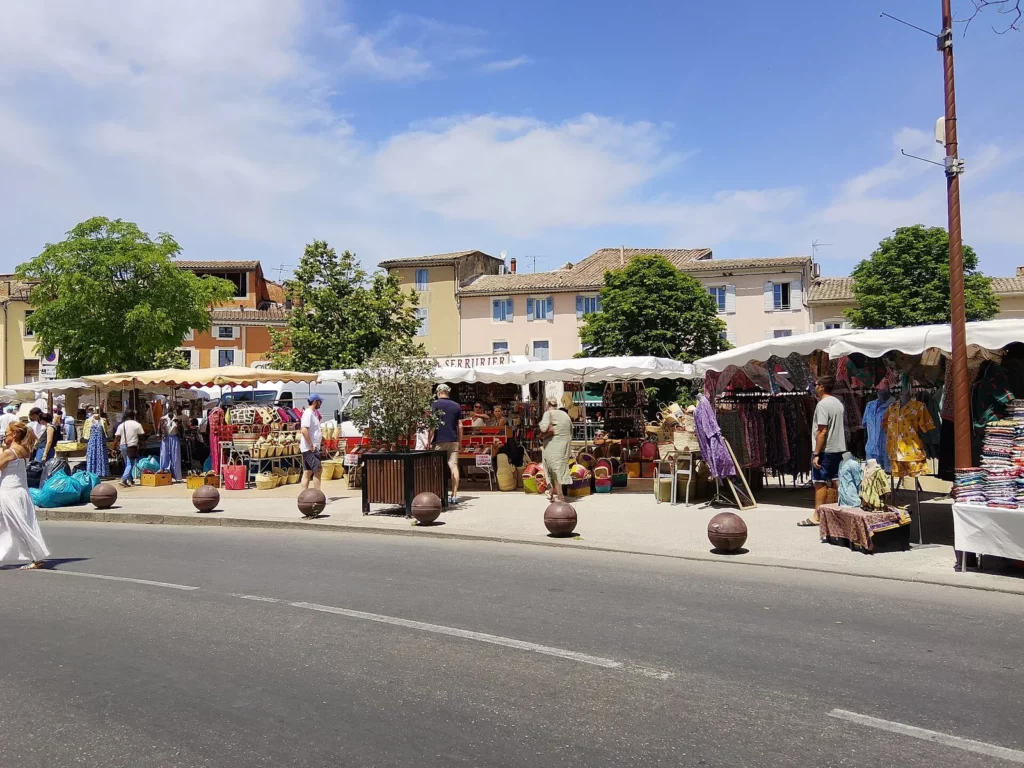 Étals colorés du marché du dimanche sous le soleil à L'Isle-sur-la-Sorgue, village de Provence à découvrir au printemps