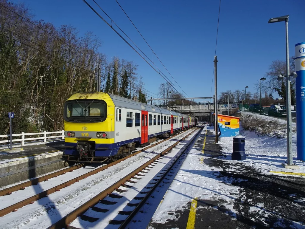 Train de la SNCB à quai sous la neige en gare de Moensberg, option économique pour voyager depuis la Belgique en janvier