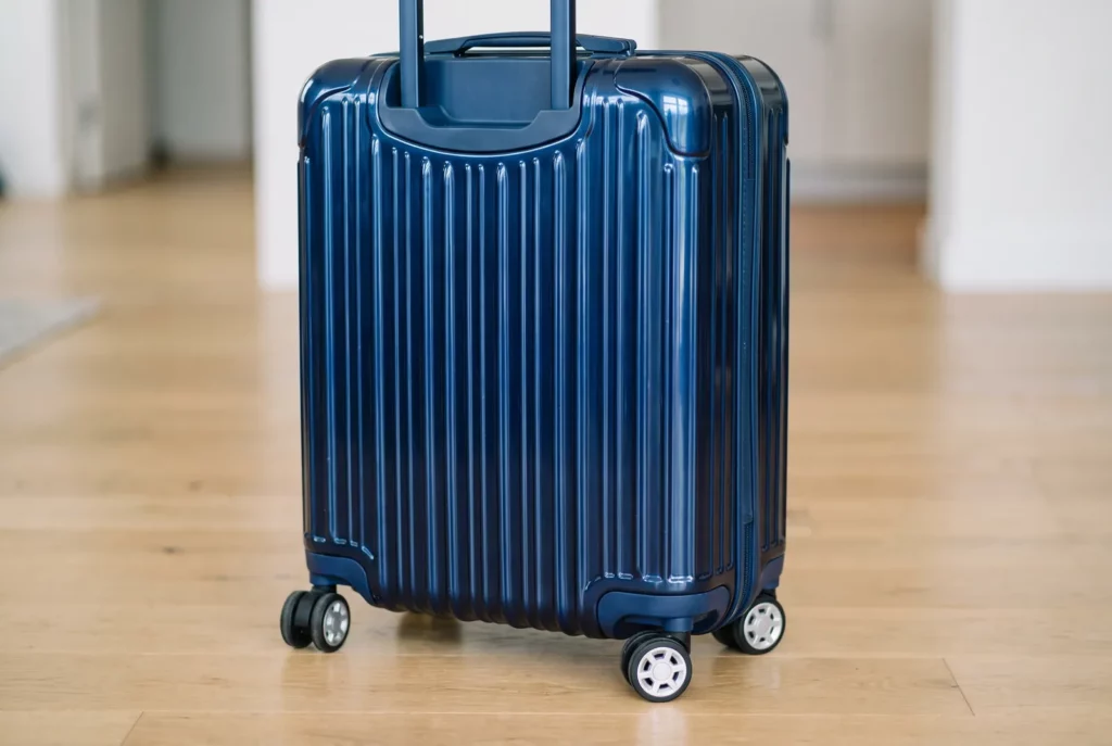 Gros plan sur la coque nervurée et légère d'une valise cabine rigide, avec ses roues pivotantes et sa poignée