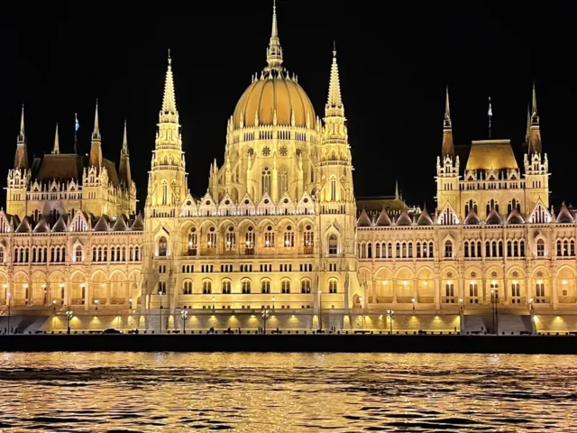 Le Parlement de Budapest illuminé la nuit, vu depuis le bateau sur le Danube