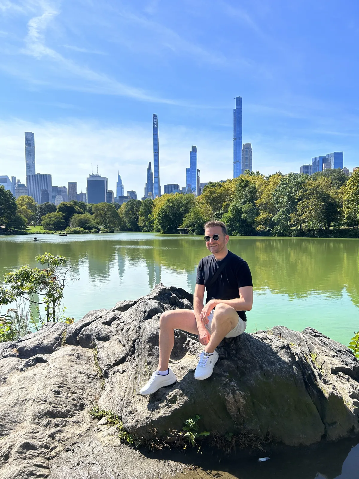 New York en 5 jours : mon carnet de voyage et mes conseils testés sur place 24 Mike assis sur un rocher au bord du Lake de Central Park, skyline de Midtown en fond