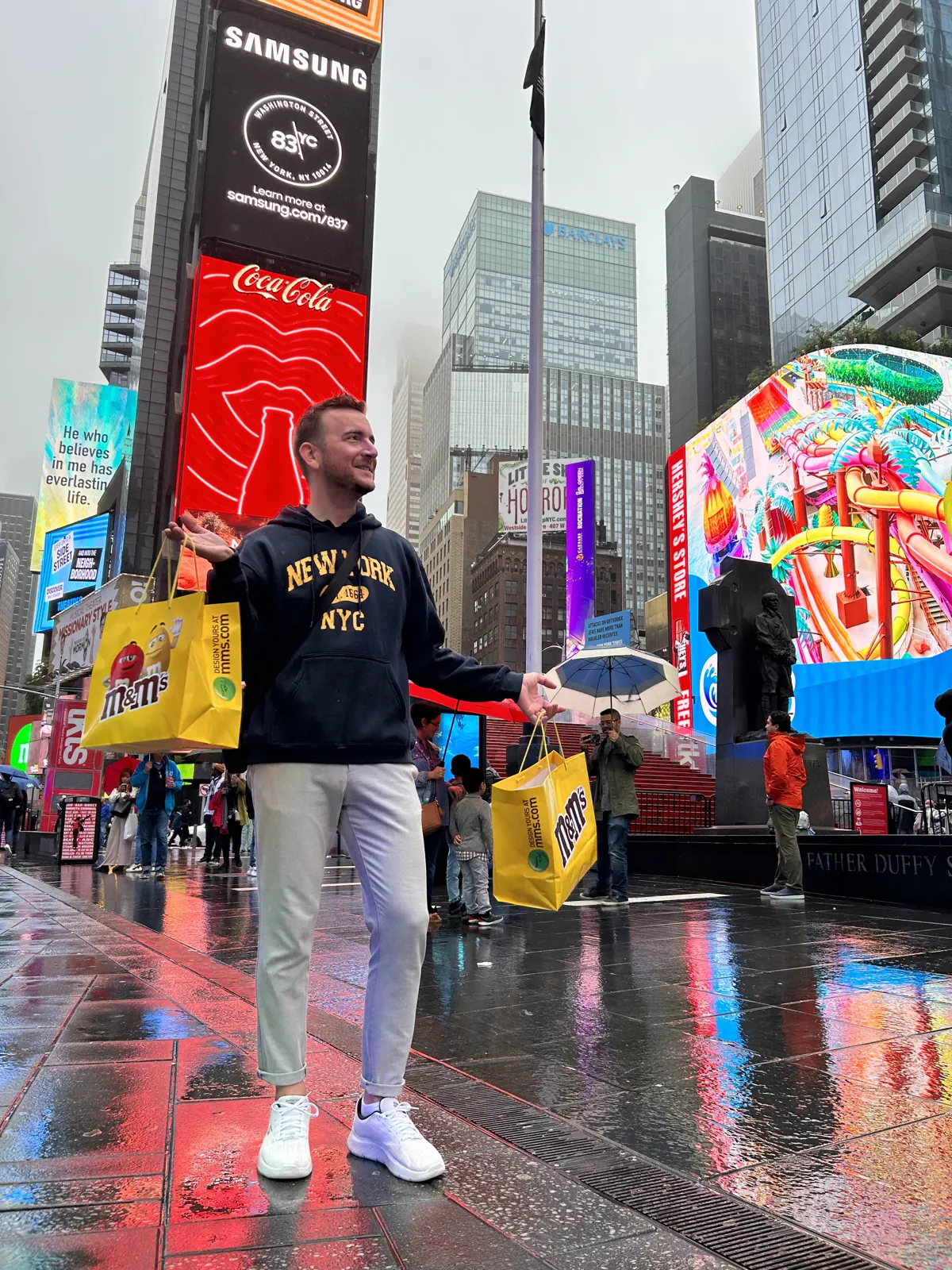 New York en 5 jours : mon carnet de voyage et mes conseils testés sur place 56 Mike en pull New York avec ses sacs M&M's à Times Square, le touriste assumé