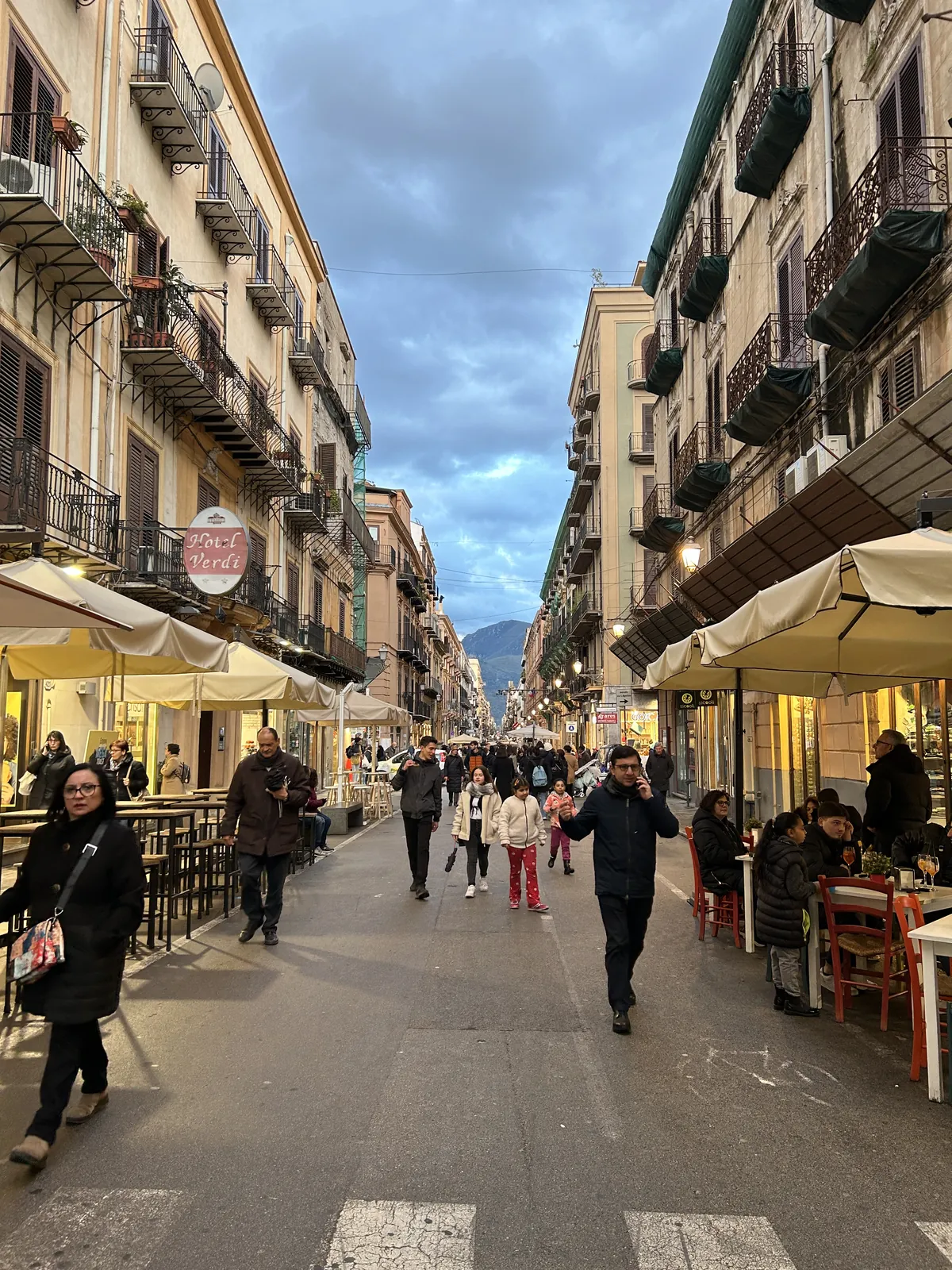 Visiter Palerme en 3 jours : mon carnet de voyage testé sur place 16 Une rue piétonne du centre en fin de journée, près du Teatro Massimo, avec les montagnes au bout